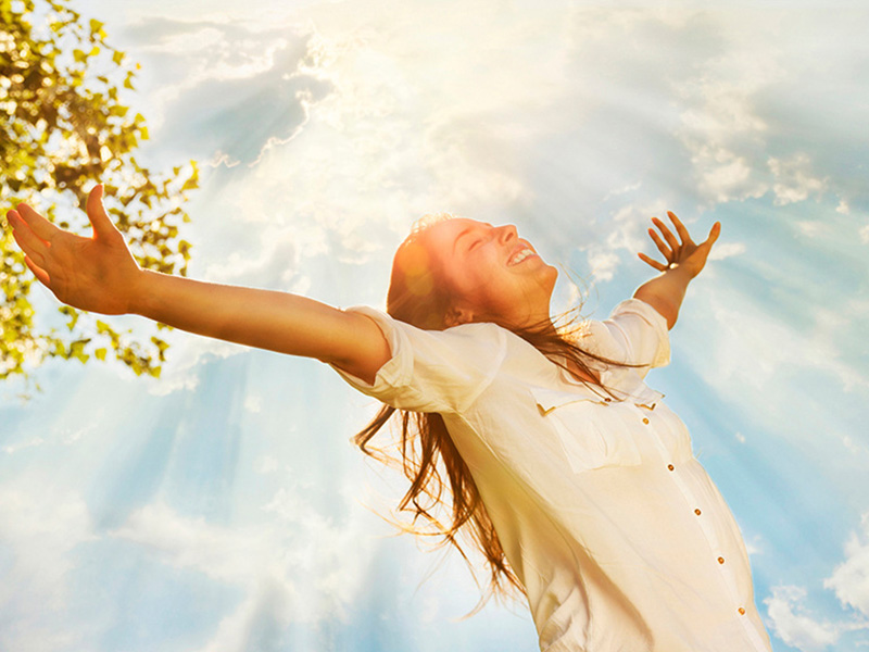 Young woman raising her arms and enjoys sunny day